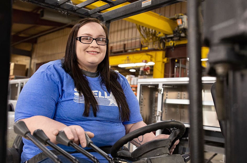 Woman in blue shirt and glasses driving machinery